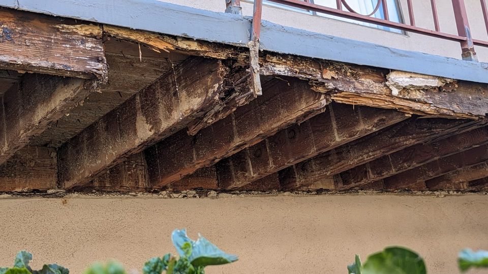 Opened walkway underside showing deteriorated wood members and connections.