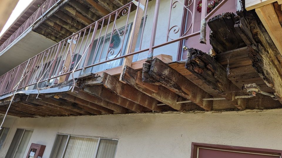 Opened Arcadia apartment walkway with existing damaged framing and selective new wood.