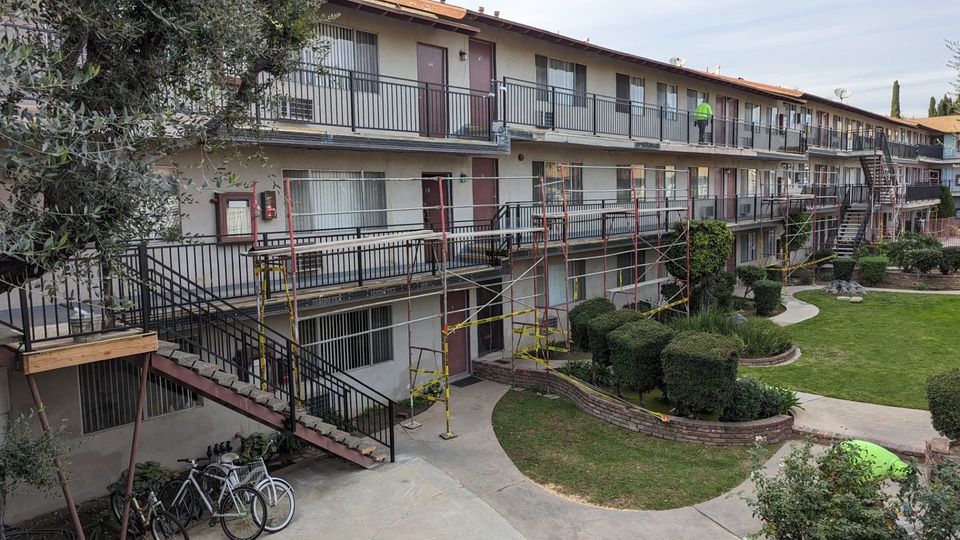 Arcadia apartment courtyard during walkway repairs with scaffolding, safety barriers and new railing sections.