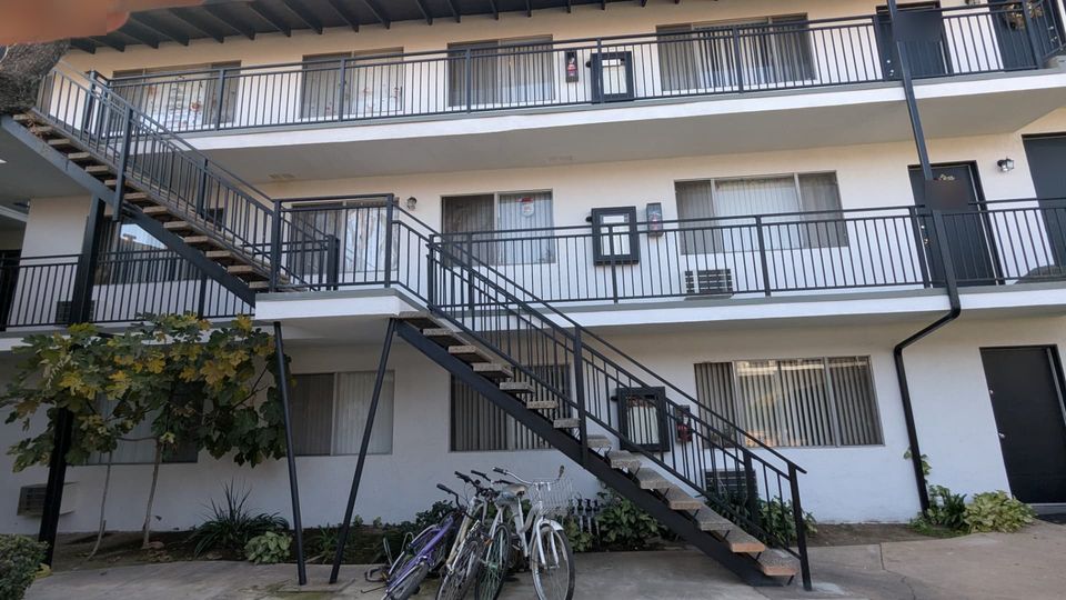 Completed apartment walkway and stair connection with dark metal railings and restored soffits.