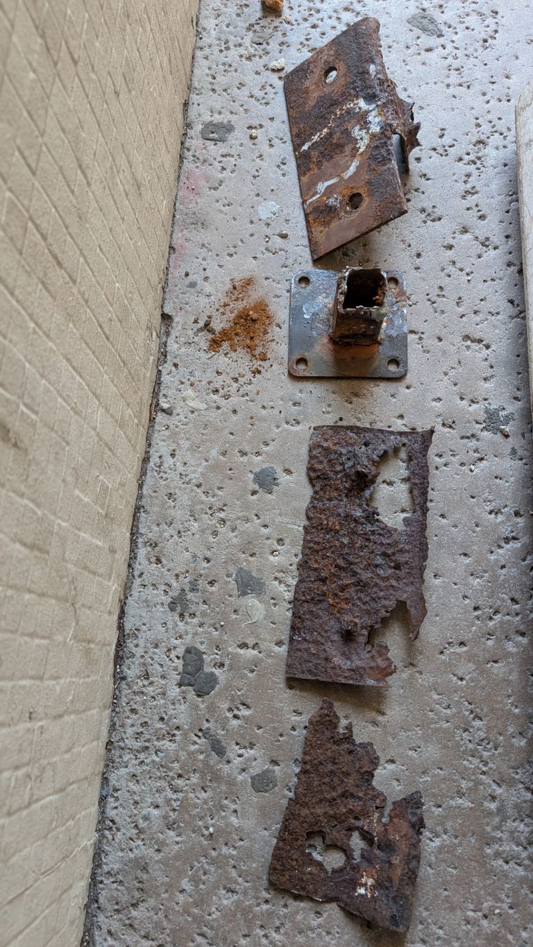 Removed corroded railing base plates and hardware laid out after balcony demolition